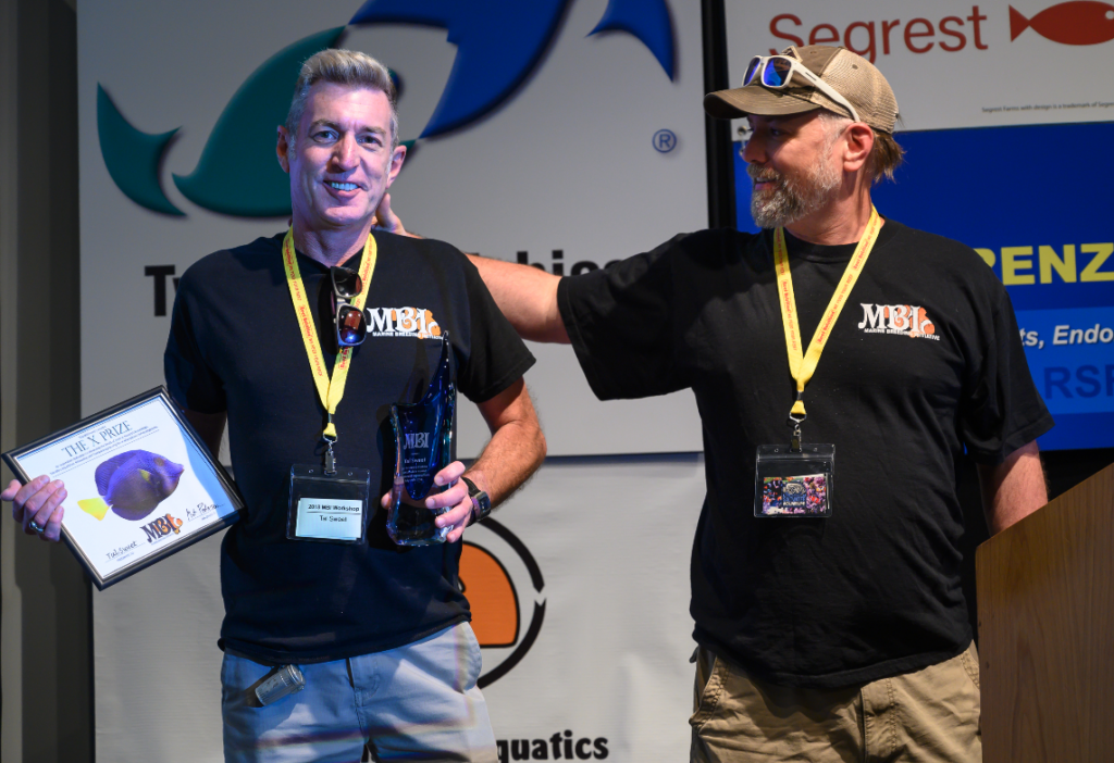 A pat on the back for a decade of marine ornamental aquaculture stewardship, Matt Pedersen (right) had the honor of presenting Tal Sweet with the Marine Breeding Initiative's X-prize and MBI Awards at the 2019 conference.