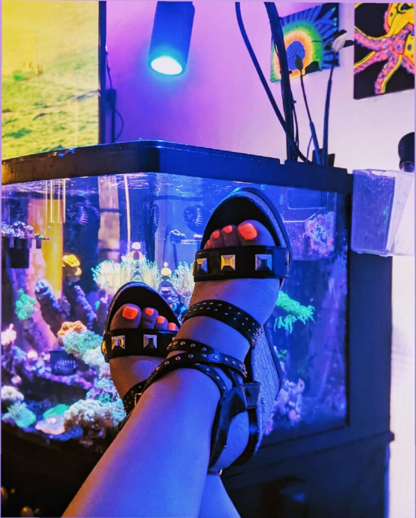 @fishanista shows off her studded platform espadrilles and UV reactive nail polish in front of her mixed reef tank.