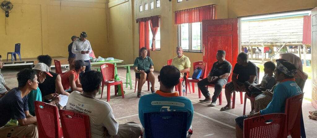 Rare's Applied Science Director Raymond Jakub (center left) speaks with village fishers, leaders, and district fishery officers in Southeast Sulawesi, Indonesia, about IndoReefFish.